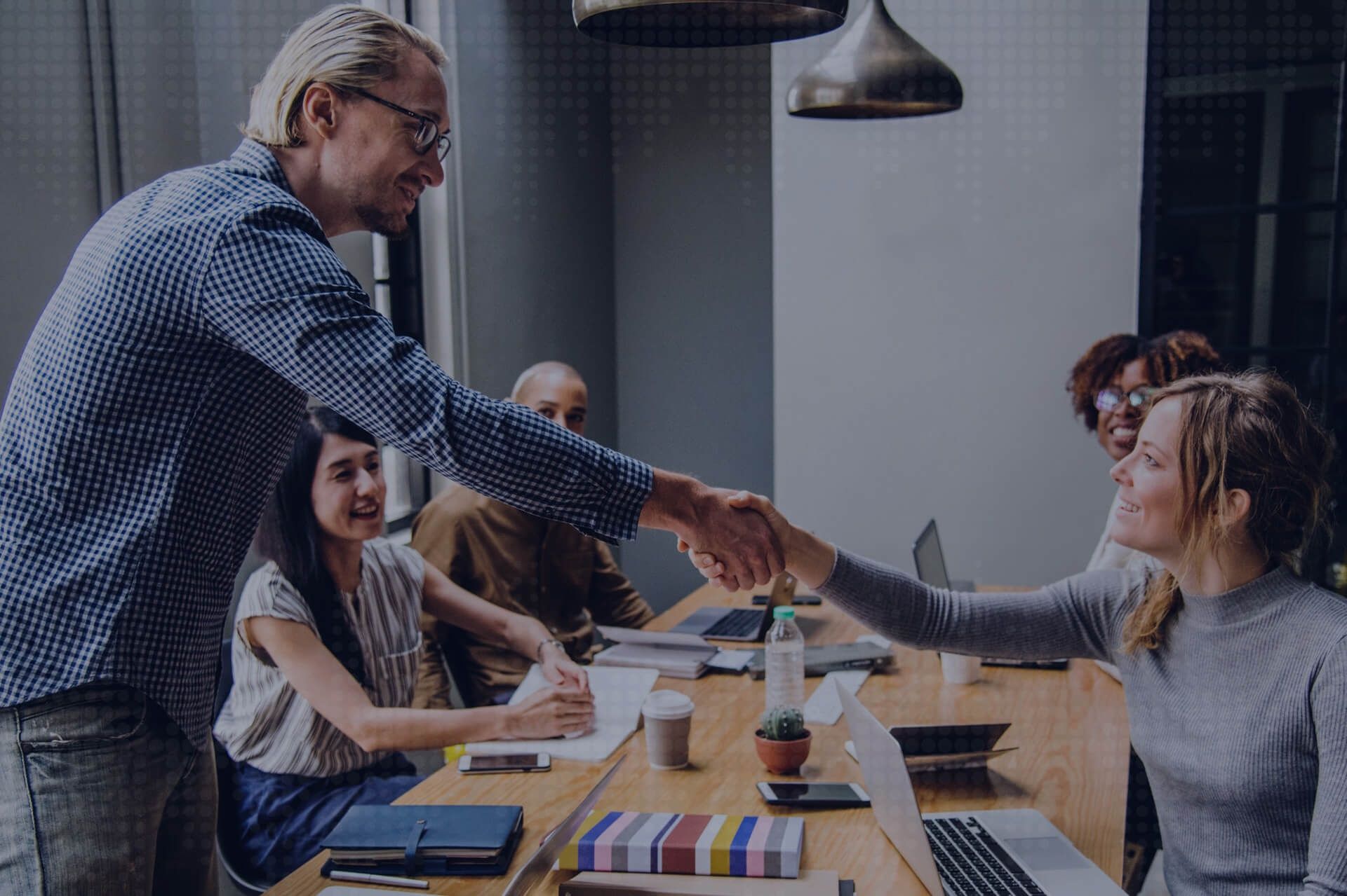 Two colleagues shaking hands across a table in a bright office