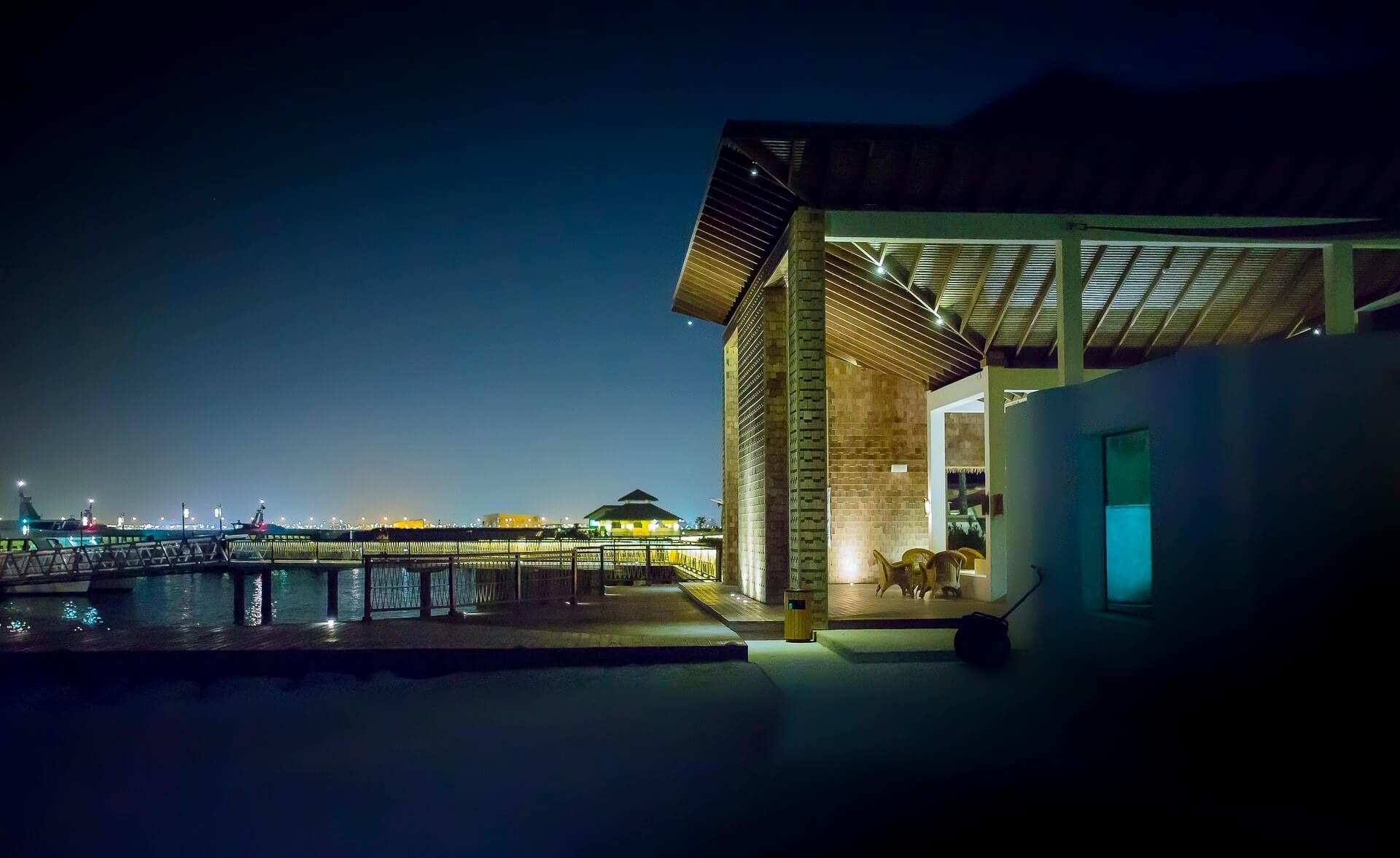 Resort pier and pavilion lit at night beside dark water